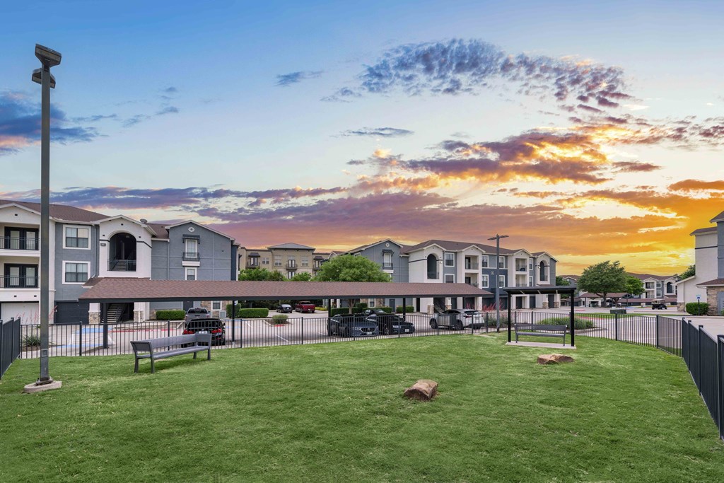 a sunset behind a row of town houses with a grassy yard