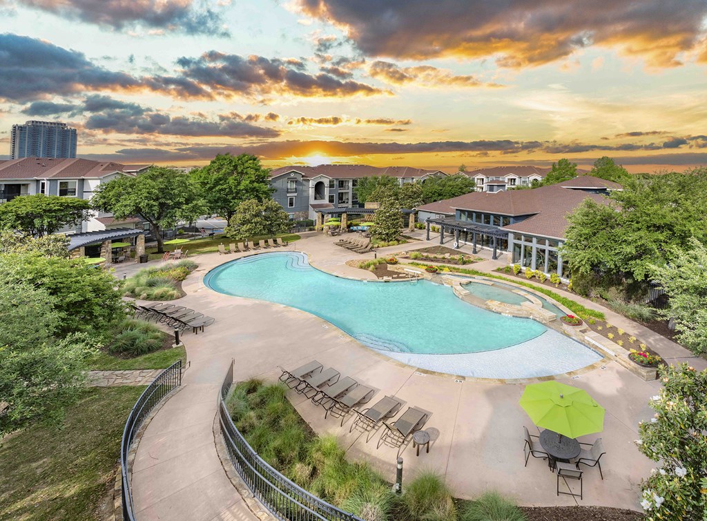 a swimming pool at a resort with a sunset in the background