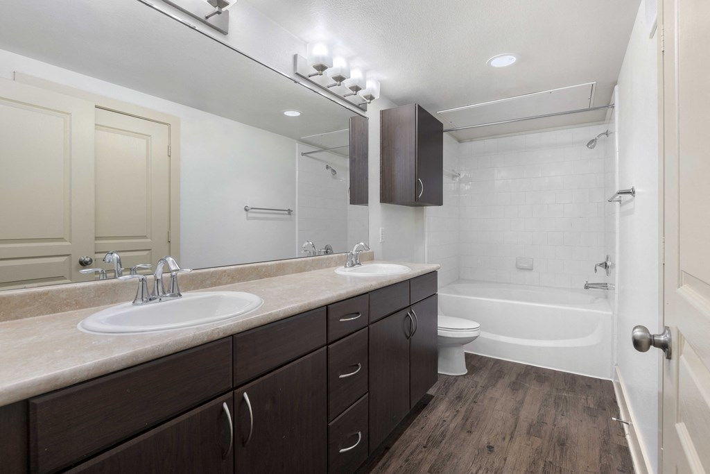 A bathroom with a white sink and brown cabinets.