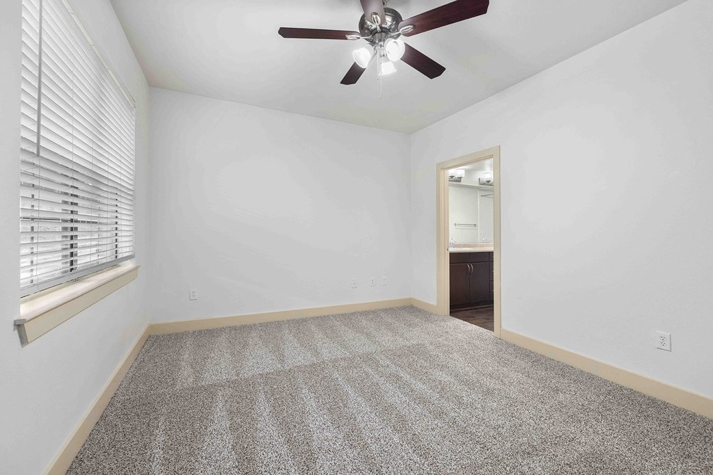 A room with a ceiling fan and carpeted floor.