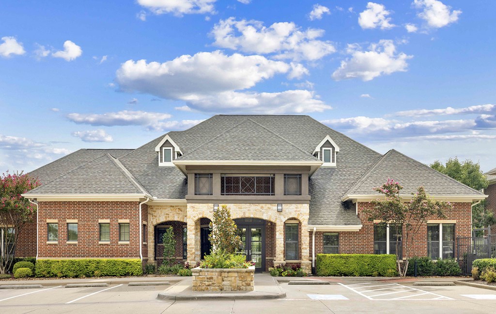 A large house with a grey roof and a fountain in front.
