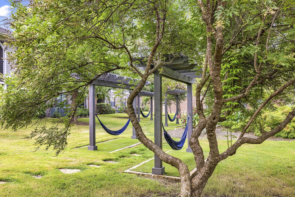 A tree in a grassy area with a structure behind it.