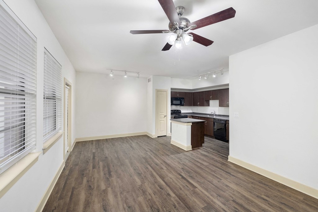 A room with a ceiling fan and wooden flooring.