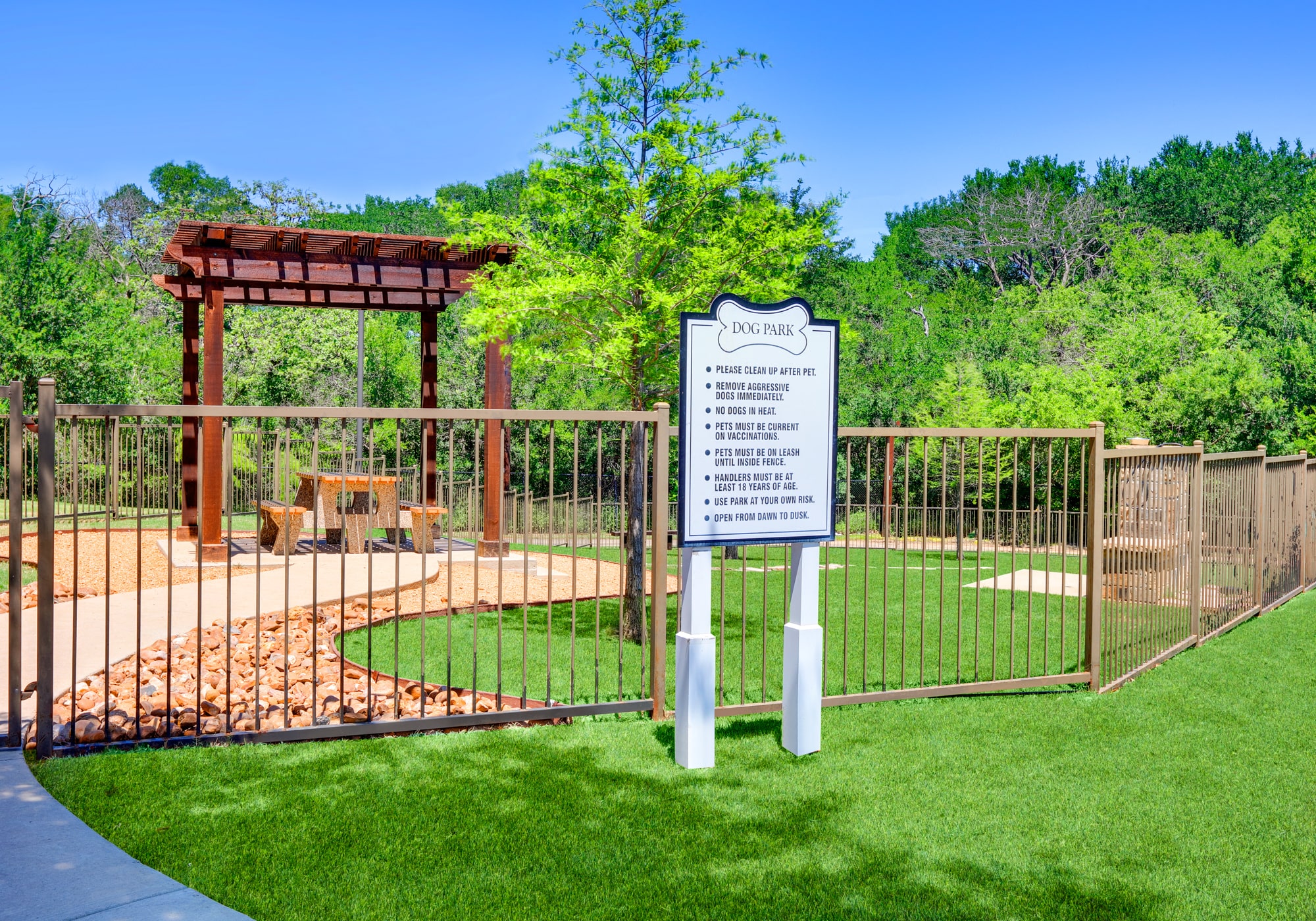 a park with a sign and a fence and a gazebo