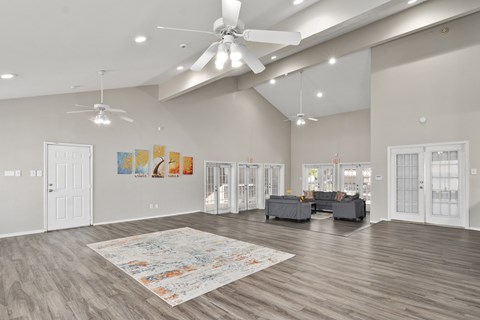 A spacious living room with a rug on the floor and a ceiling fan above.
