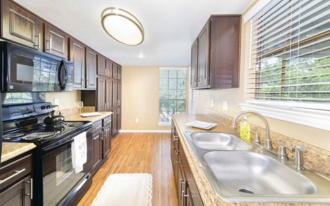 A kitchen with dark wood cabinets and a black stove top oven.