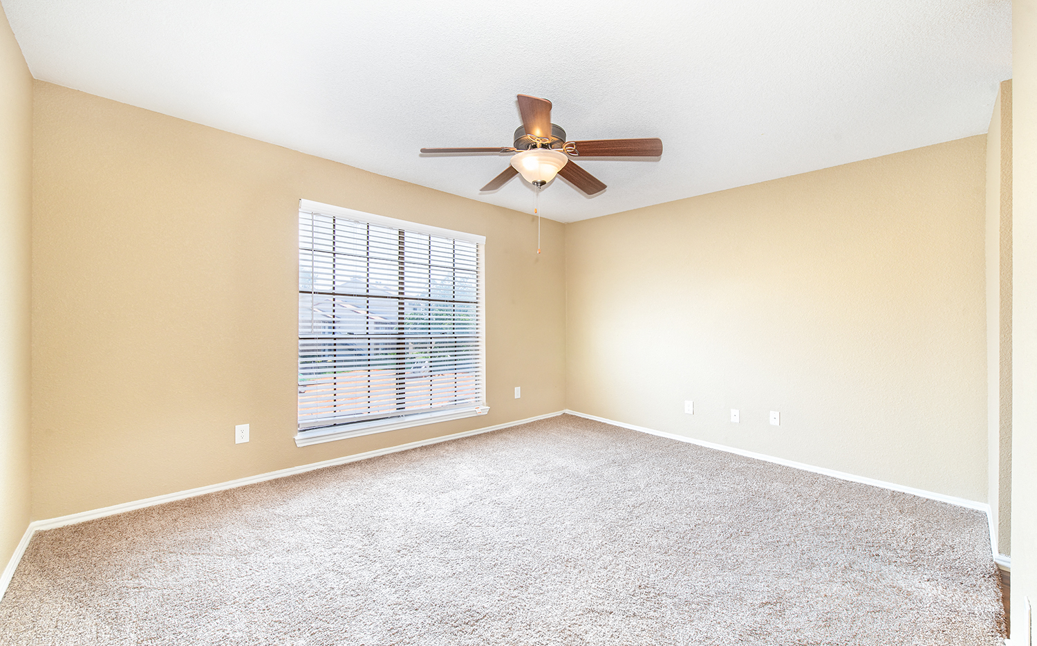 an empty living room with a ceiling fan and a window