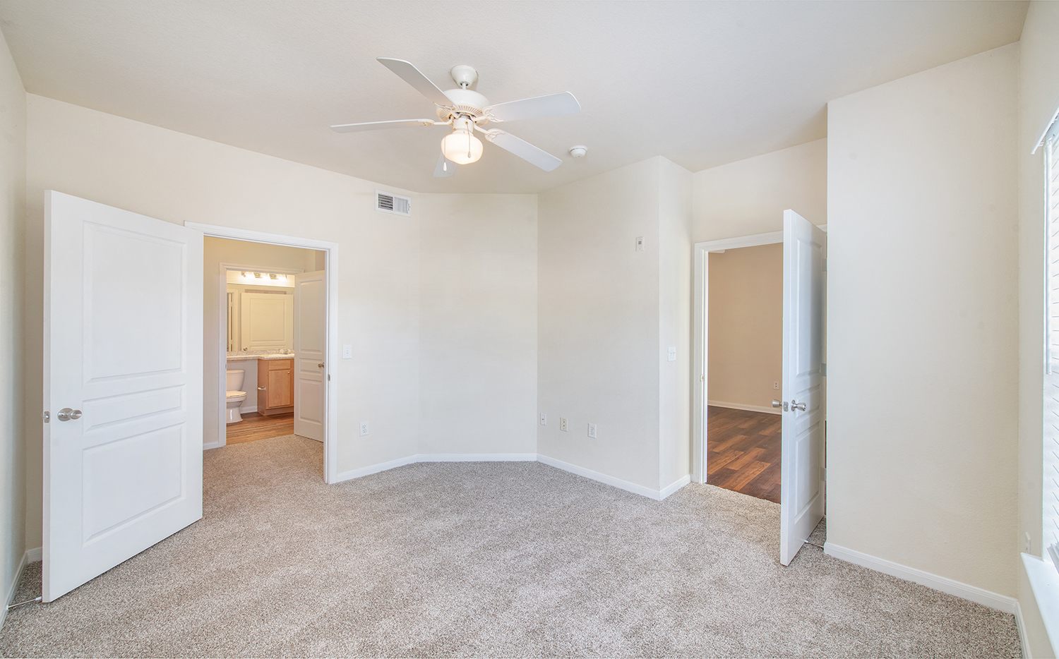 a spacious living room with white walls and a ceiling fan