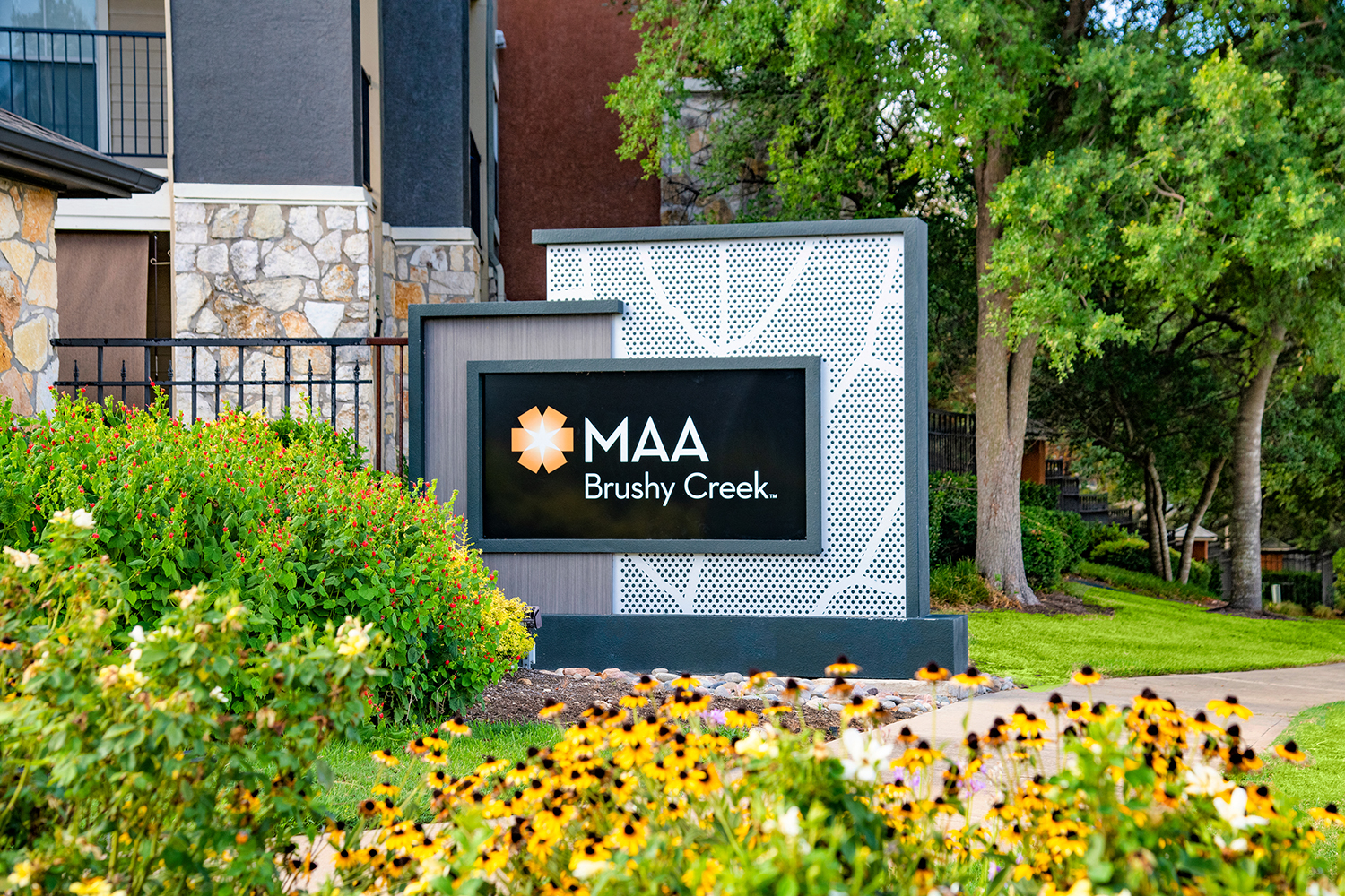 a sign for the mia bushy creek building in front of flowers