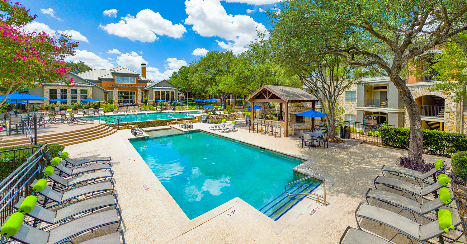 a resort style pool with chairs and umbrellas in front of a house