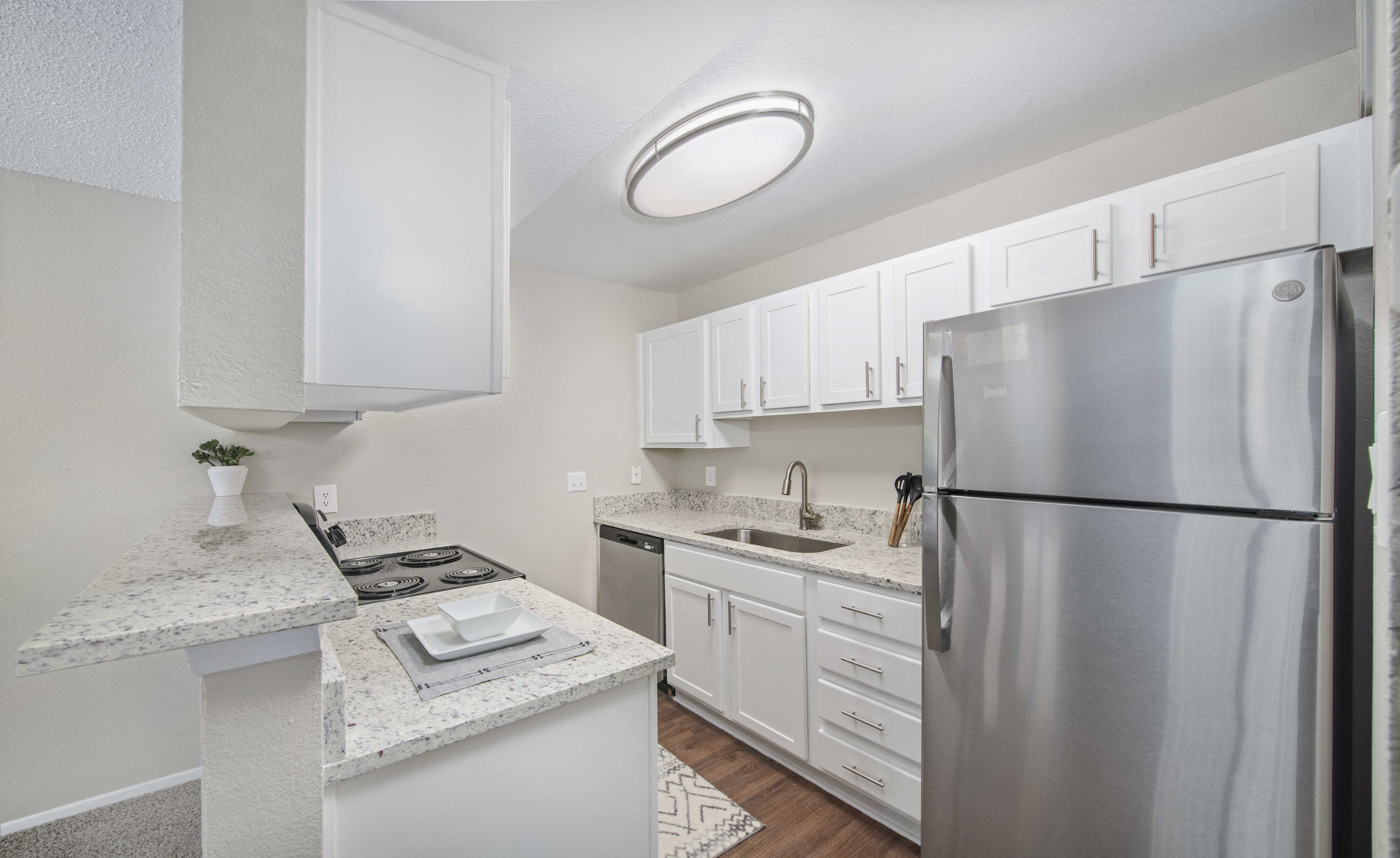 a kitchen with white cabinets and a stainless steel refrigerator