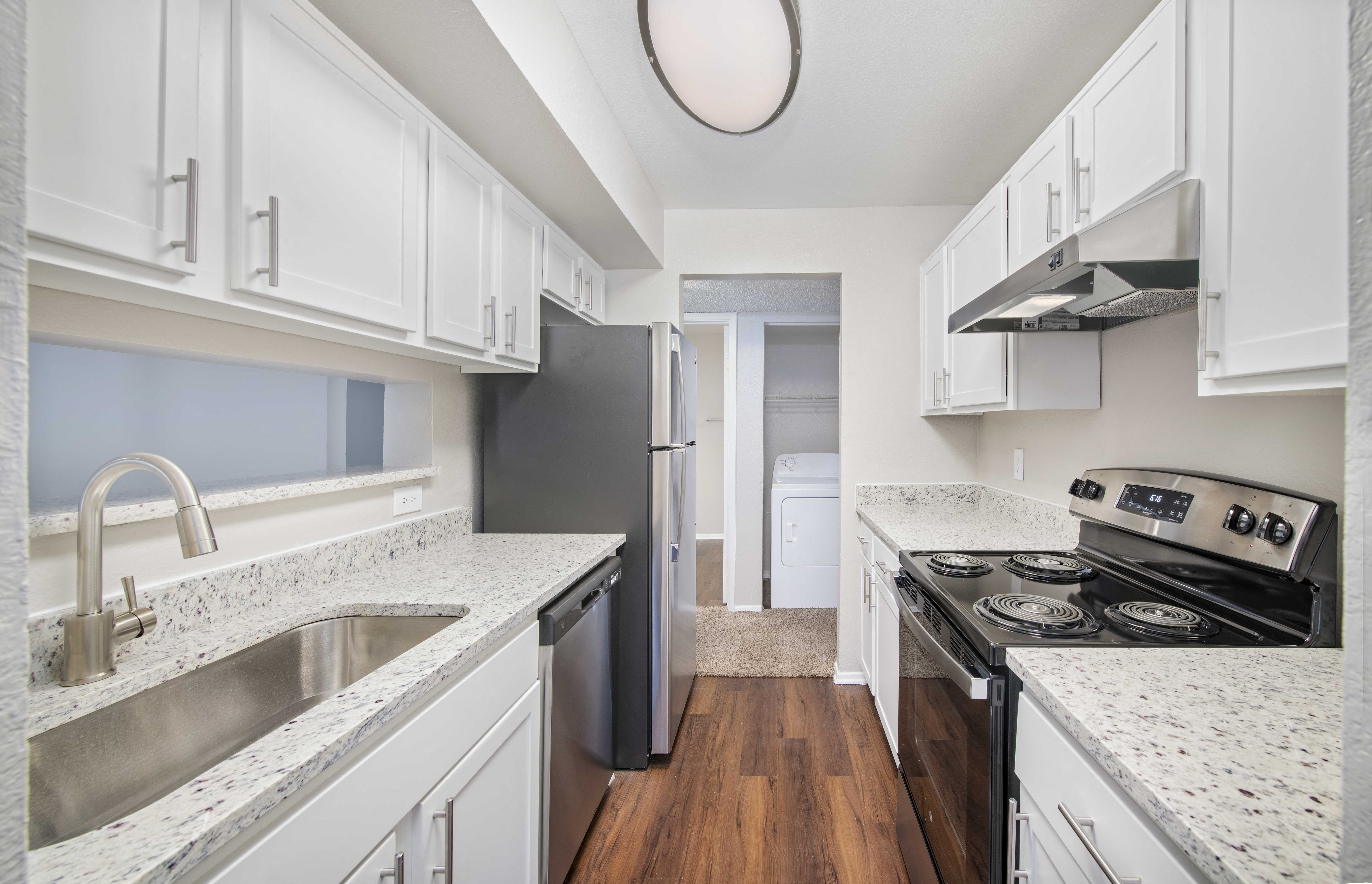 a kitchen with white cabinets and granite counter tops and stainless steel appliances