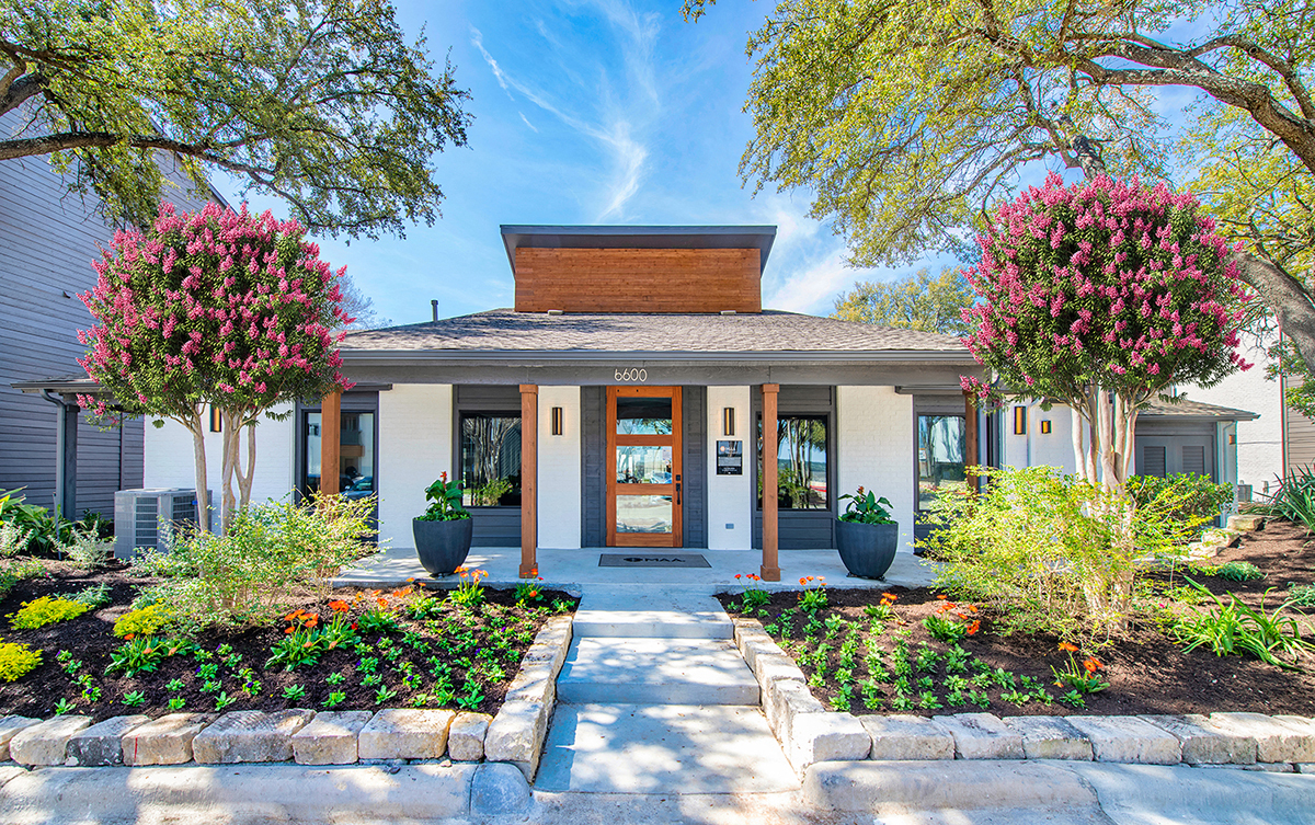 the front entrance of a house with trees and plants