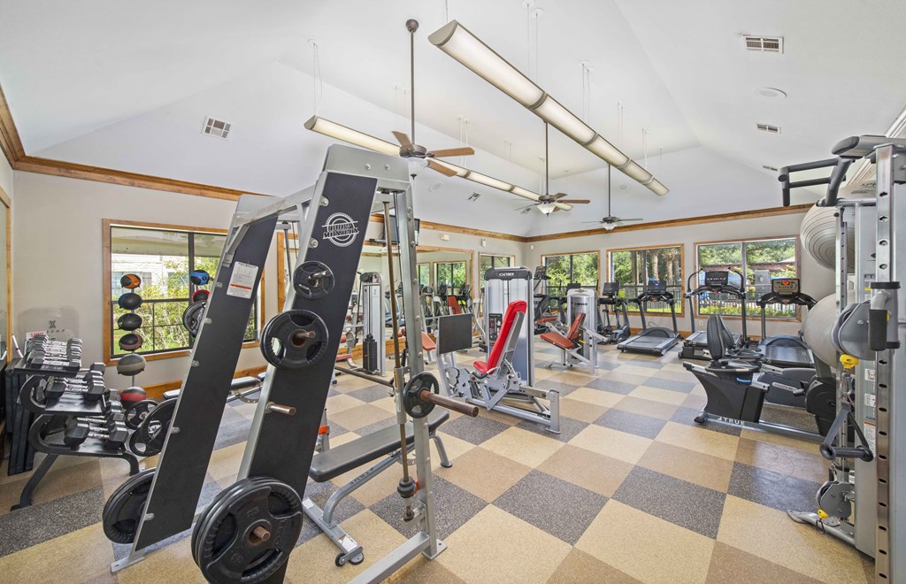 a gym with weights and other equipment in a room with windows