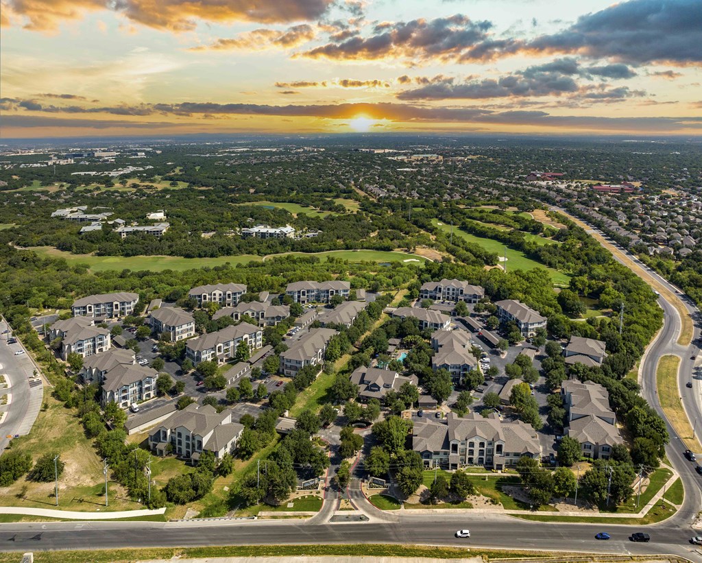 an aerial view of a neighborhood of houses with the sun setting over the city