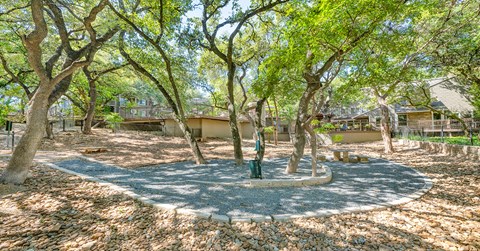 A tree-filled park with a circular playground in the middle.