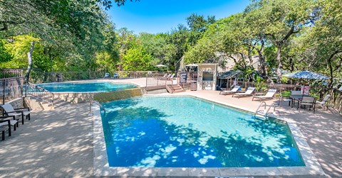 A large swimming pool surrounded by trees and lounge chairs.