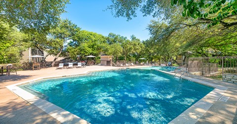 A large swimming pool surrounded by trees and a fence.