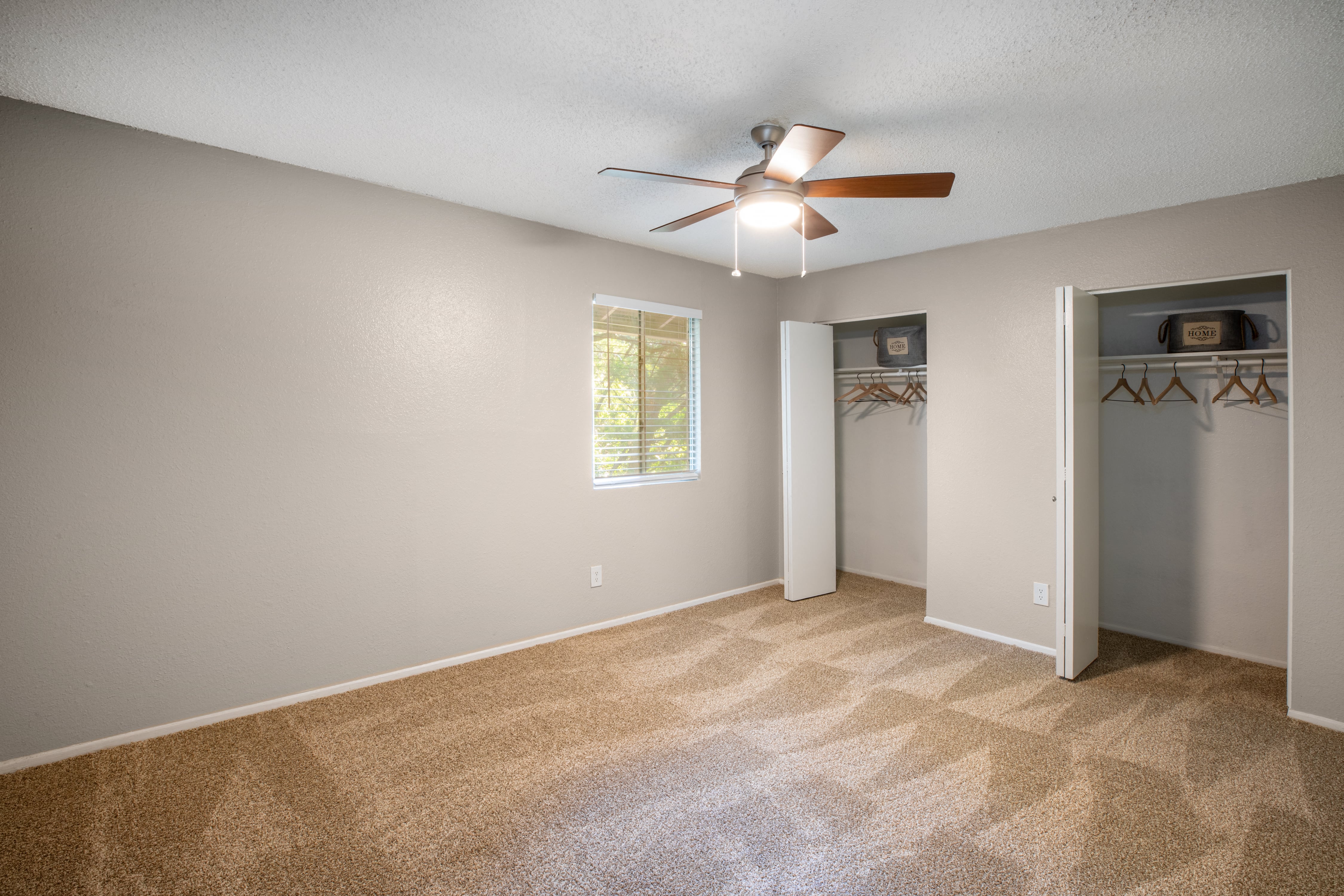 an empty living room with a ceiling fan and a closet