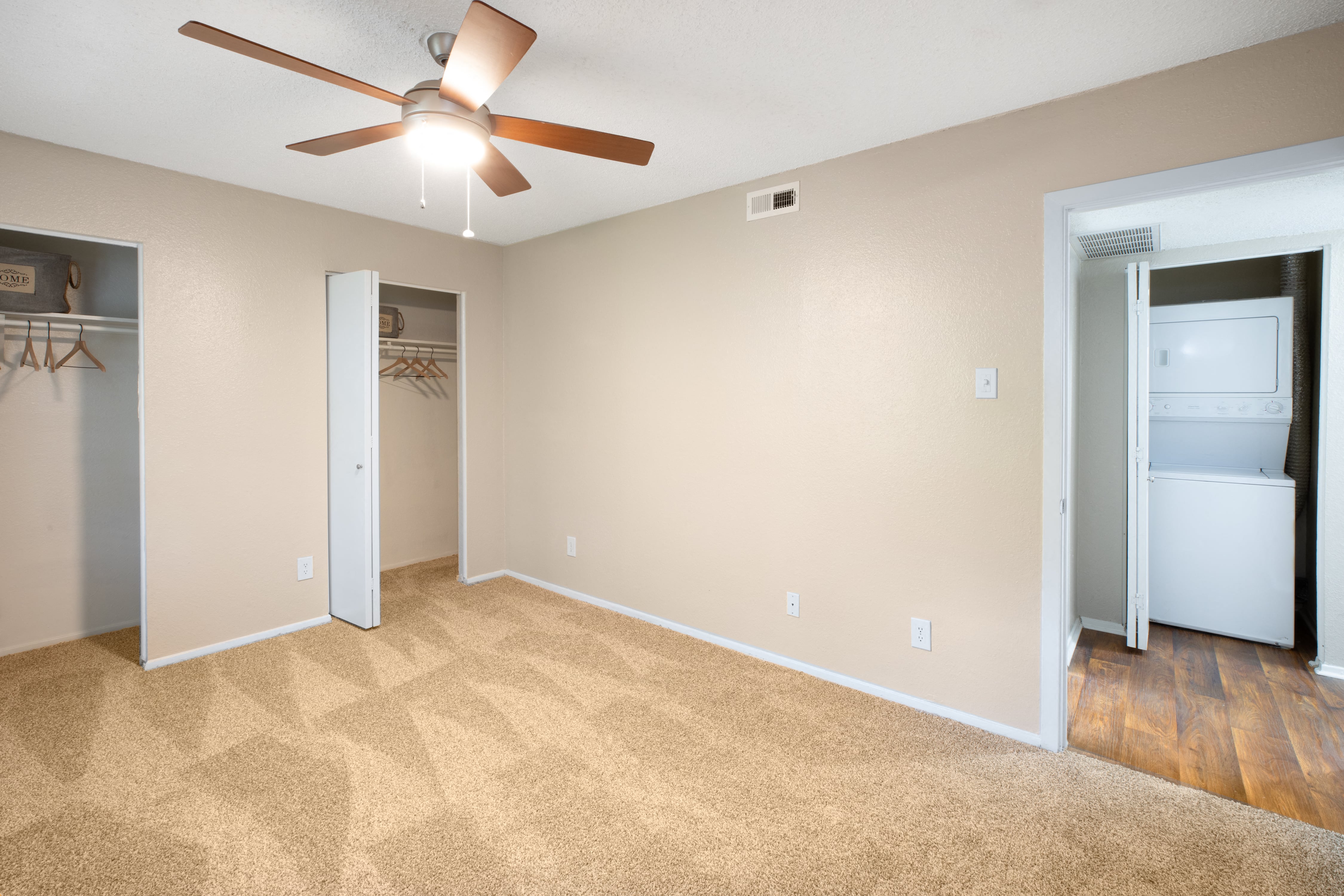an empty living room with a ceiling fan and a closet