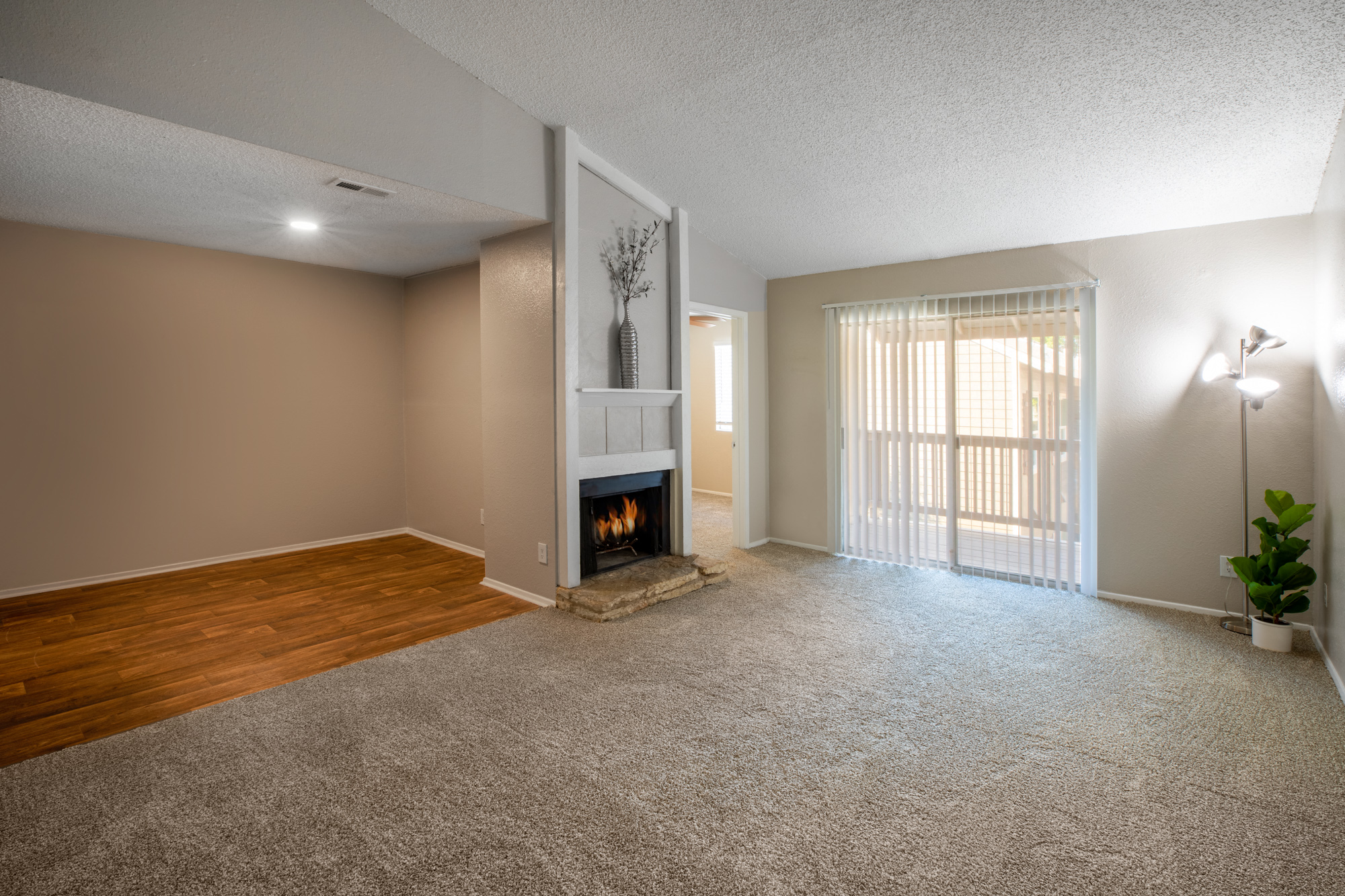 an empty living room with a fireplace and a sliding glass door