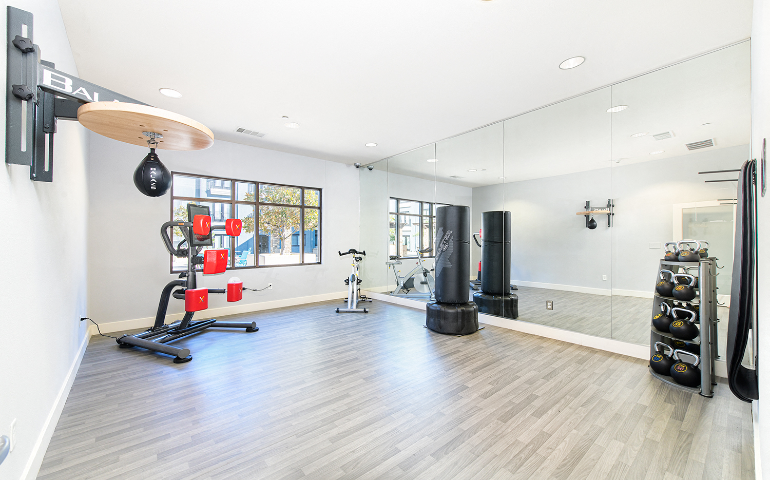 the exercise room has a large window and floor to ceiling mirrors