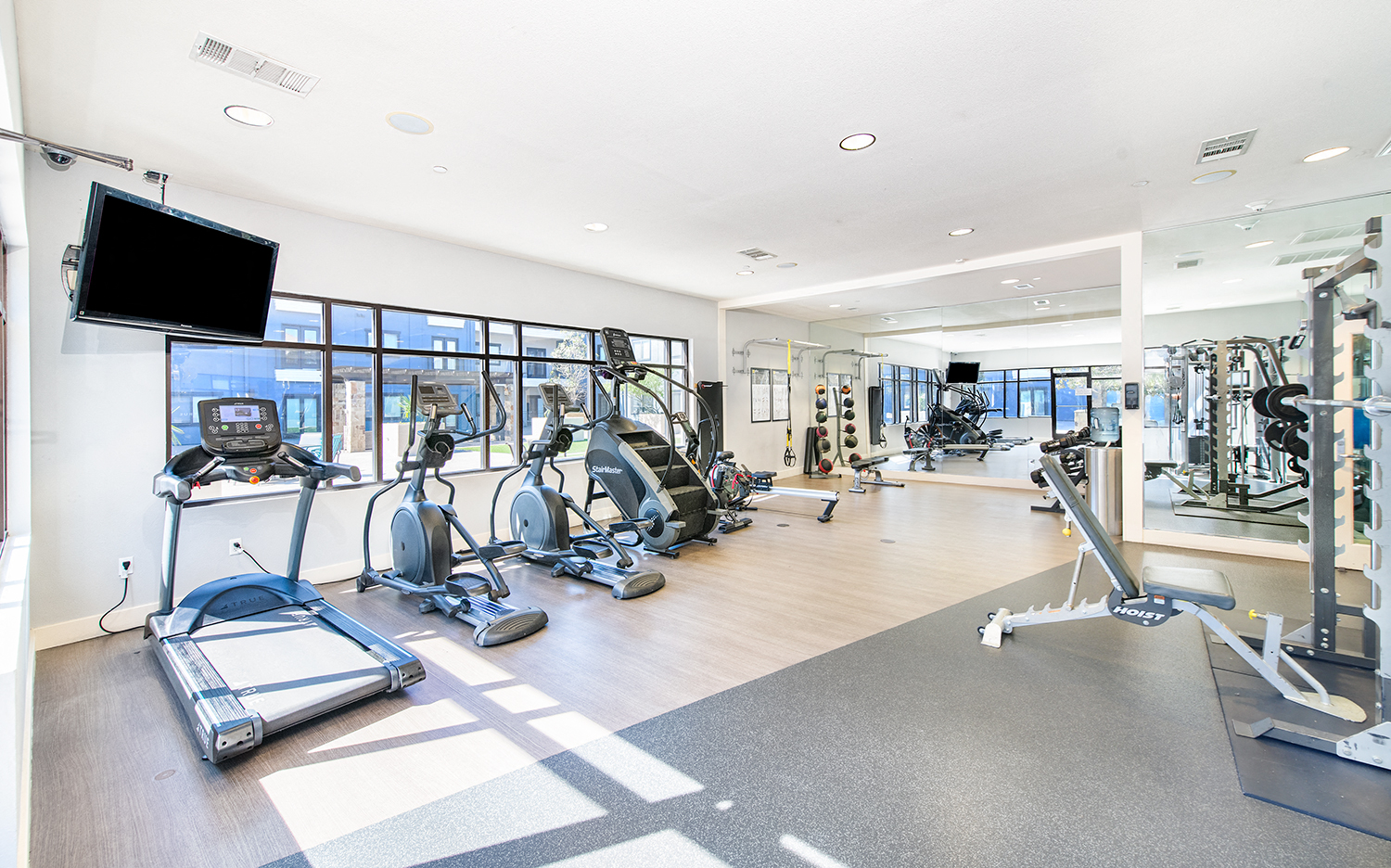 a gym with cardio equipment and a tv in a building