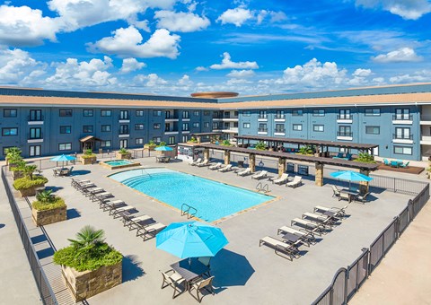 an overhead view of an outdoor pool with chairs and umbrellas