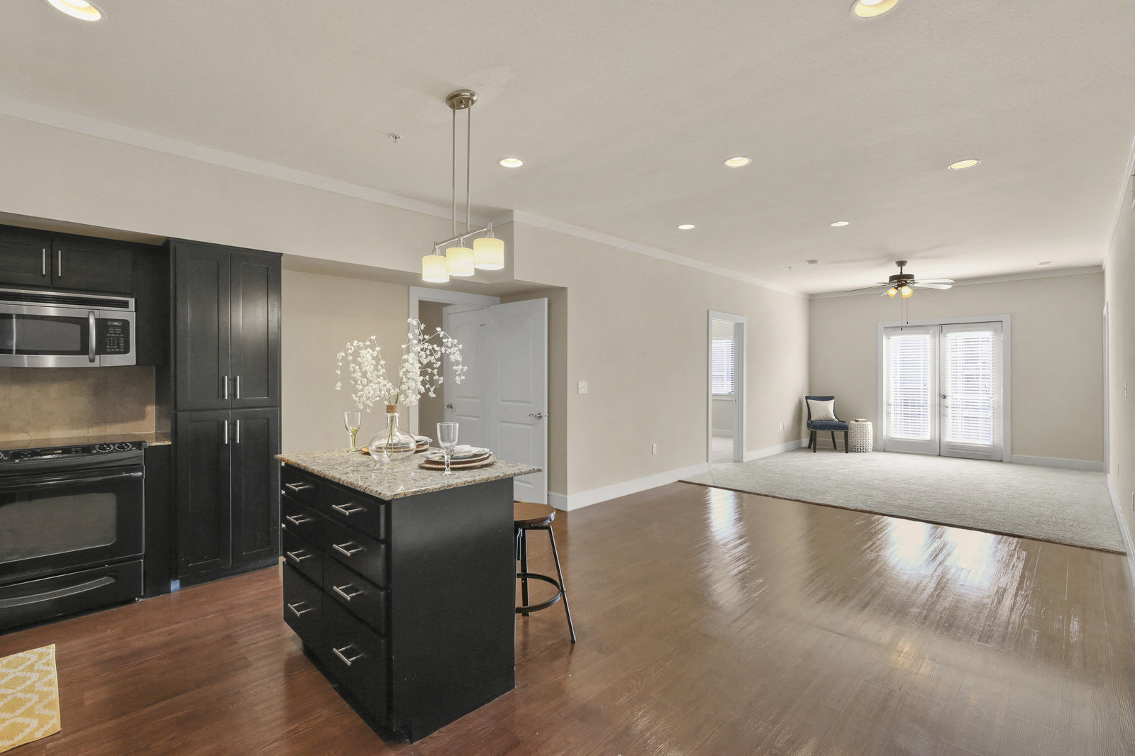 an open kitchen and living room with black cabinets and a black island