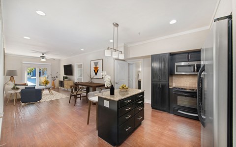 a kitchen with a center island and a living room with a table and chairs