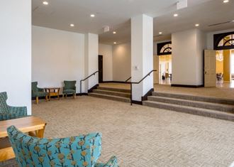 the lobby of a hotel with stairs and chairs