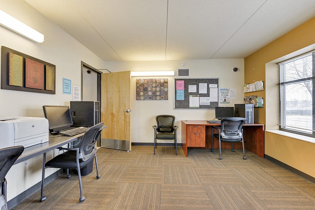an office with a computer and a desk with chairs