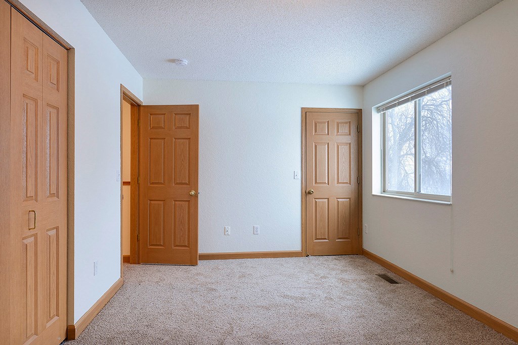 an empty room with two doors and a window