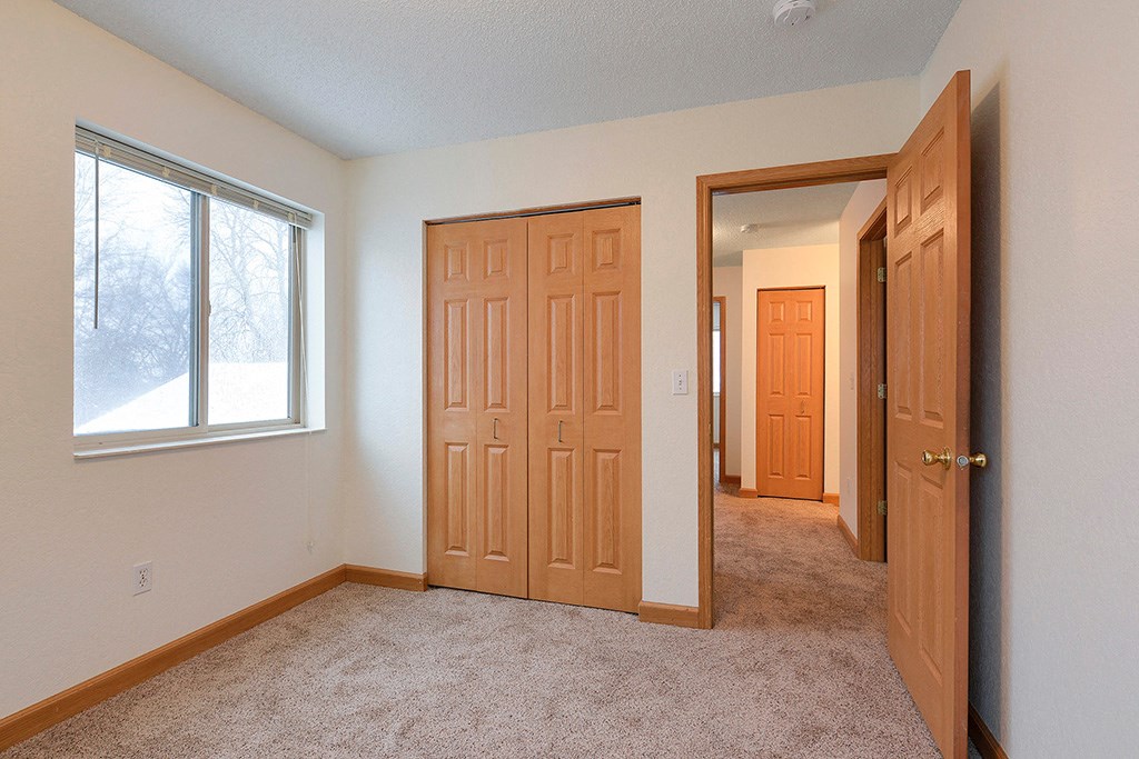 a bedroom with a closet and a door and a window
