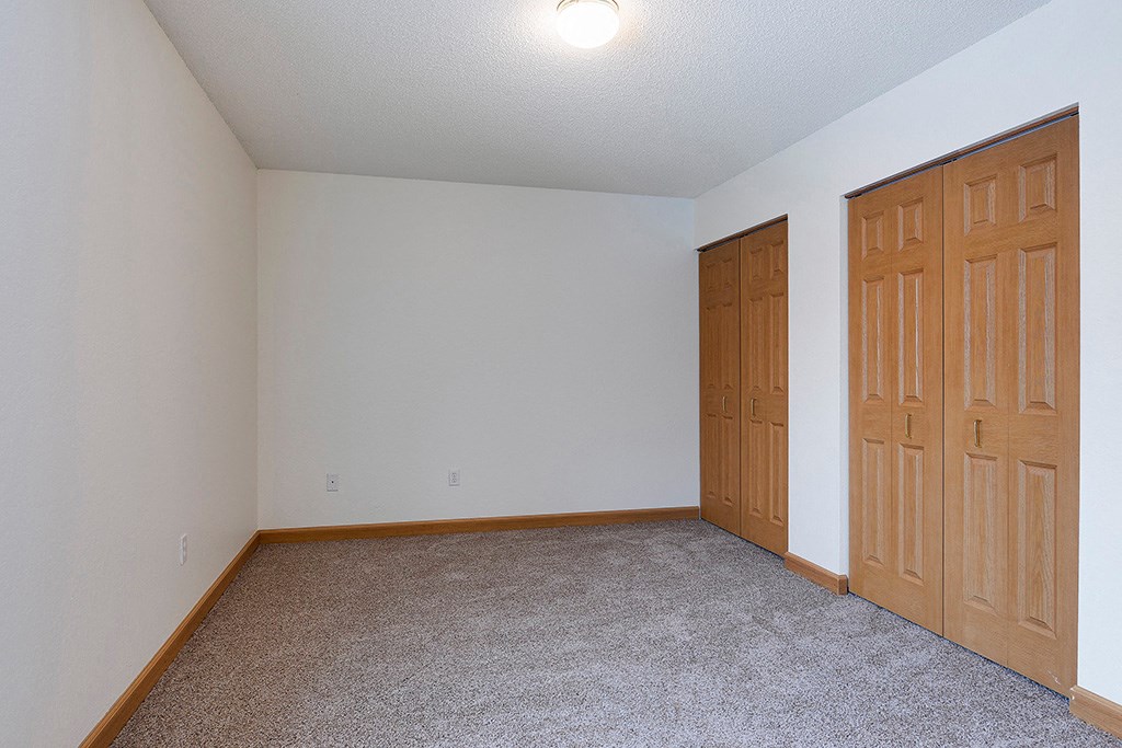 an empty room with two doors and a carpeted floor