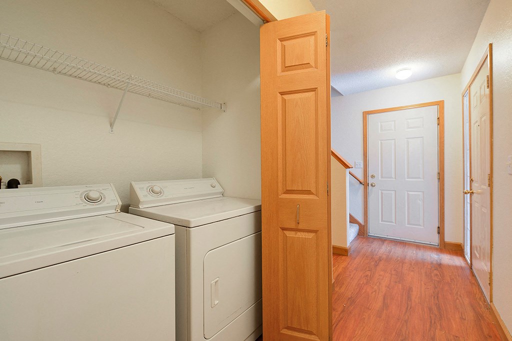 a room with two washers and dryers in it and a door to a