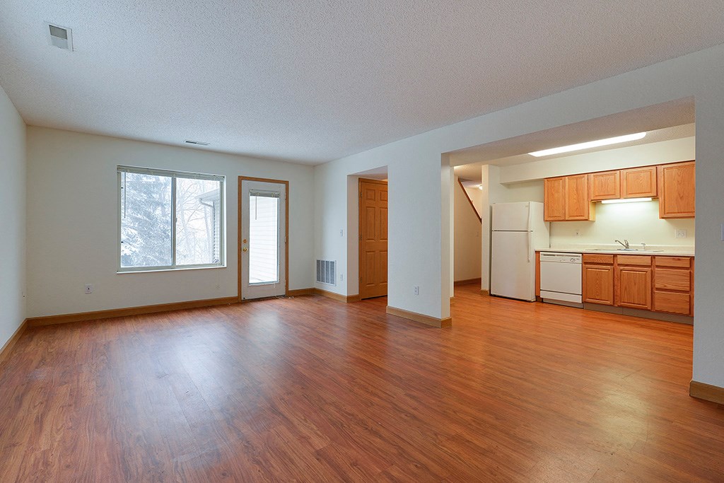 an empty living room and kitchen with wood floors