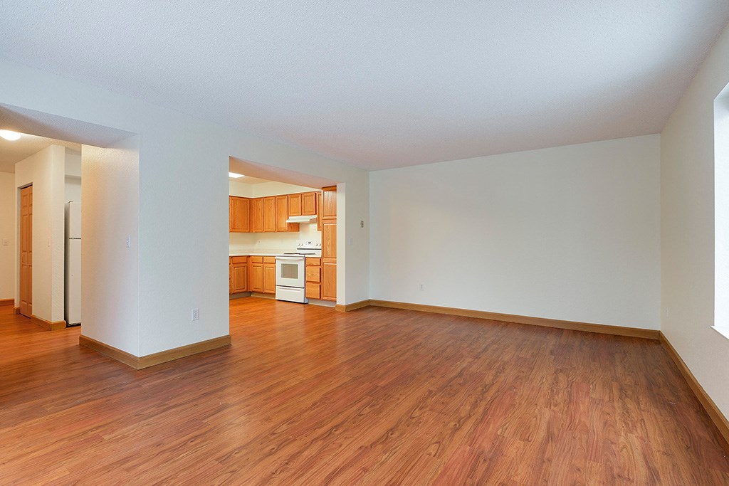 an empty living room and kitchen with wood floors