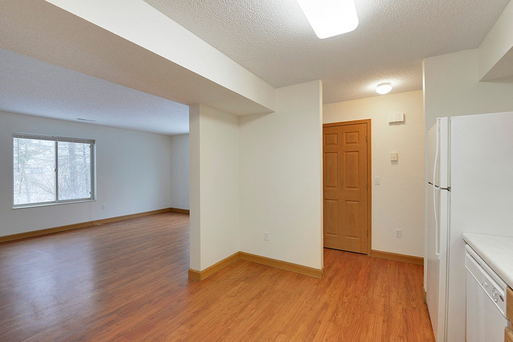 an empty living room with a refrigerator and a door