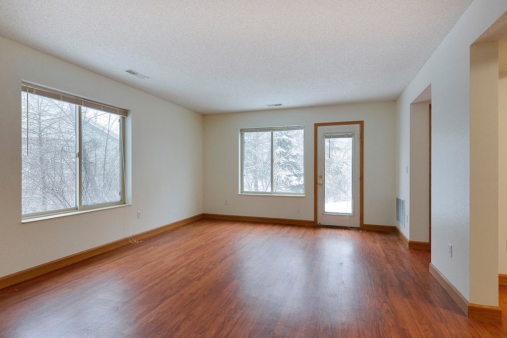 an empty living room with wood floors and windows