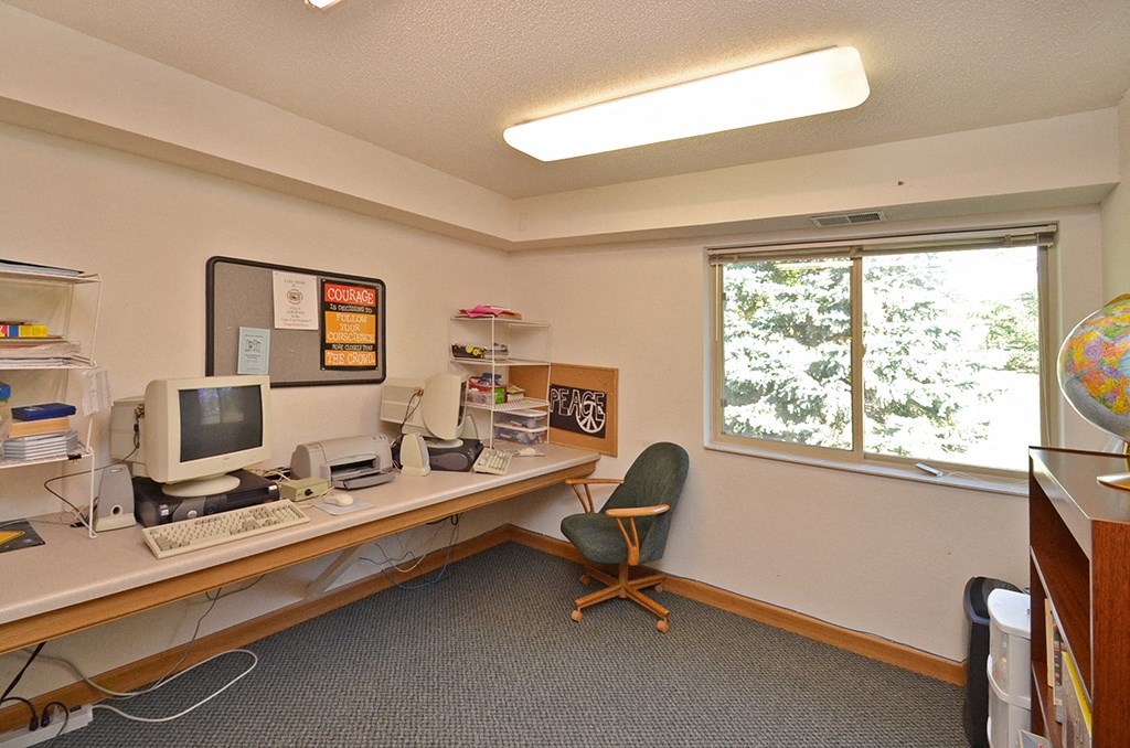 a desk with a computer and a chair in a room