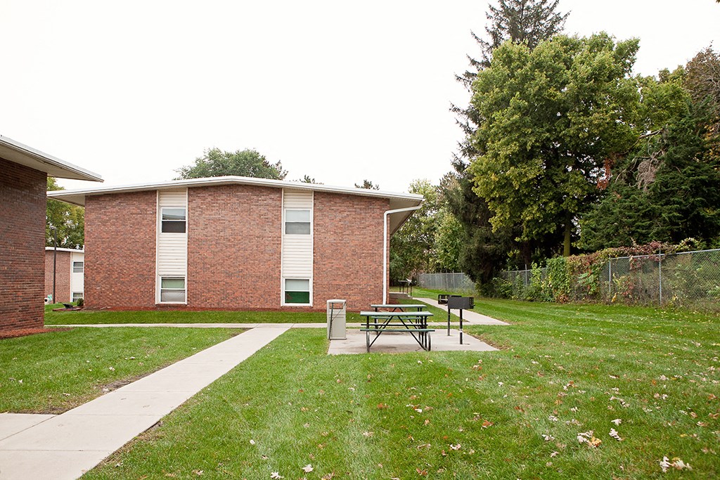 a picnic table in a yard in front of a brick building