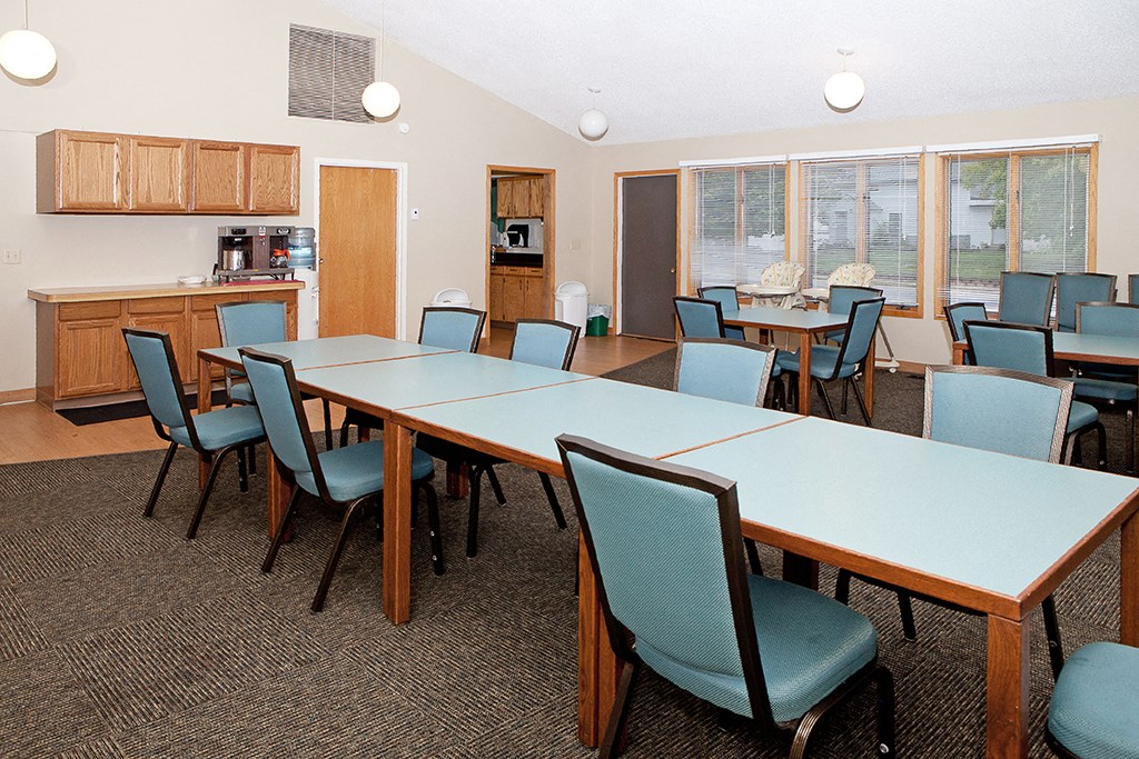 a conference room with a long table and chairs and a kitchen