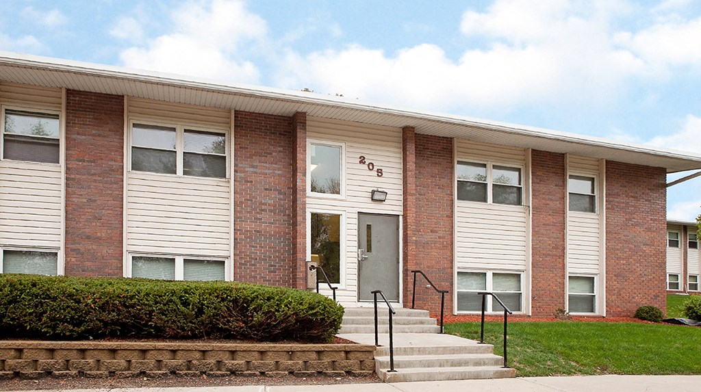 the front of a brick building with steps and a lawn