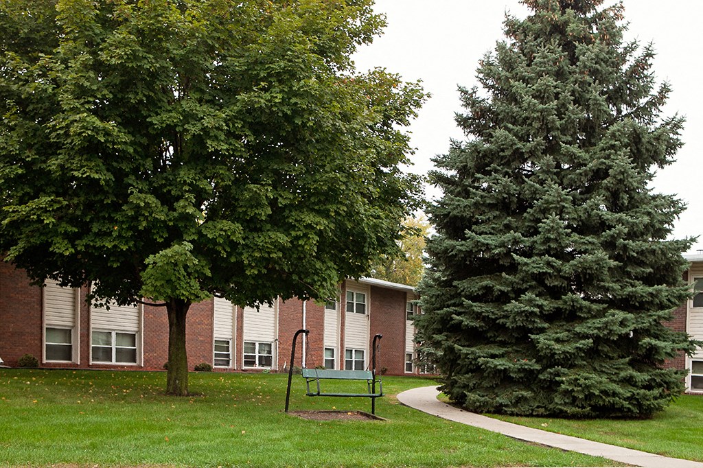 a playground and trees in front of a brick building