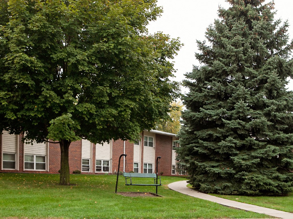 a park with a bench and trees in front of a building