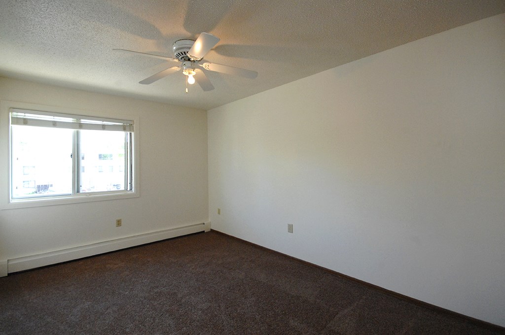 an empty room with a ceiling fan and a window