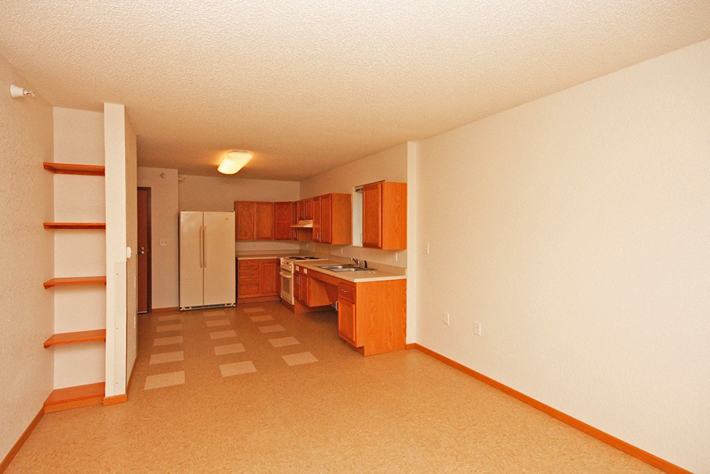 an empty kitchen with wooden cabinets and a white refrigerator
