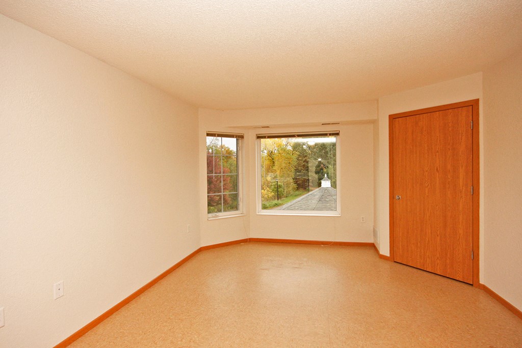 an empty living room with a large window and a wooden door