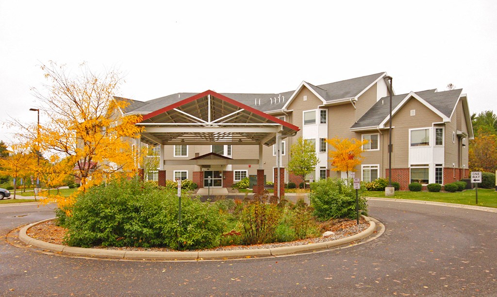 a roundabout in front of an apartment building with trees and bushes